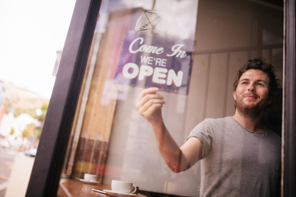 Hipster Man Turning Opening Sign on Door Coffee Shop