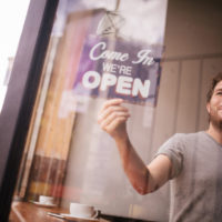 Hipster Man Turning Opening Sign on Door Coffee Shop