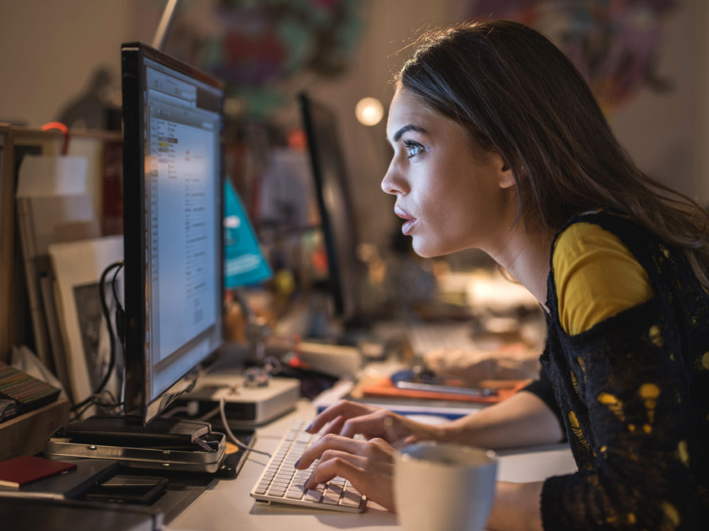 Side view of a woman staring at computer and working.