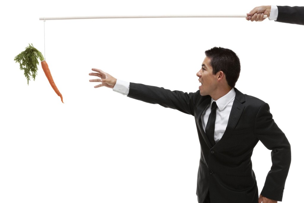 Man in suit reaching for carrot attached to string