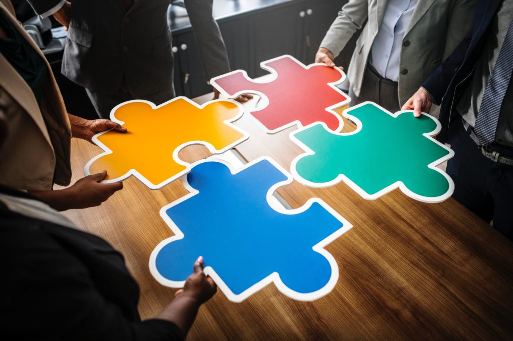 People holding large colored puzzle pieces