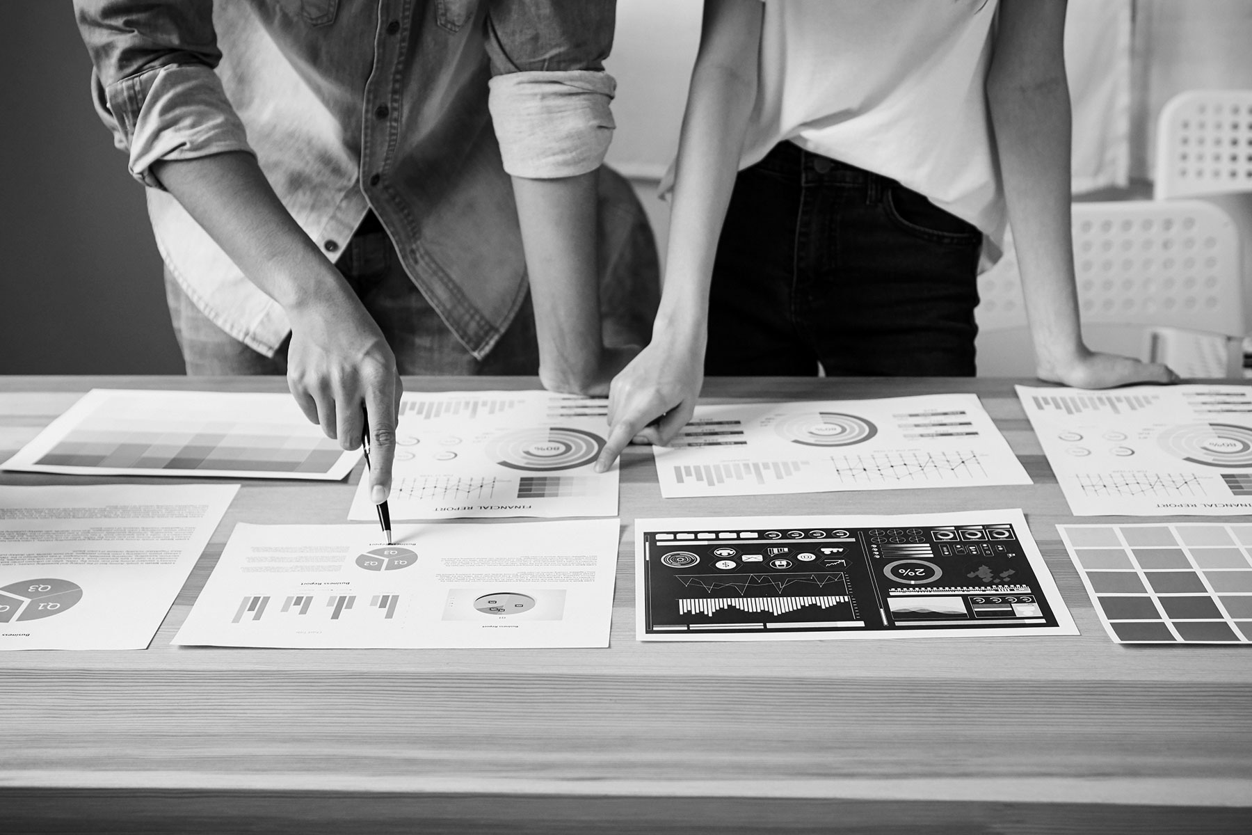 Black and white image of coworkers pointing at graphs and charts