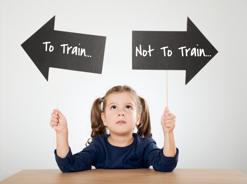 Girl holding up arrow signs that read "To Train... Not to Train..."